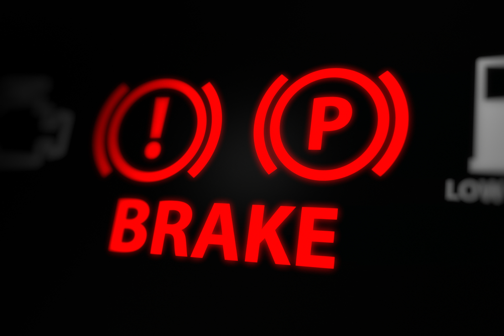 Red brake warning light illuminated on car dashboard