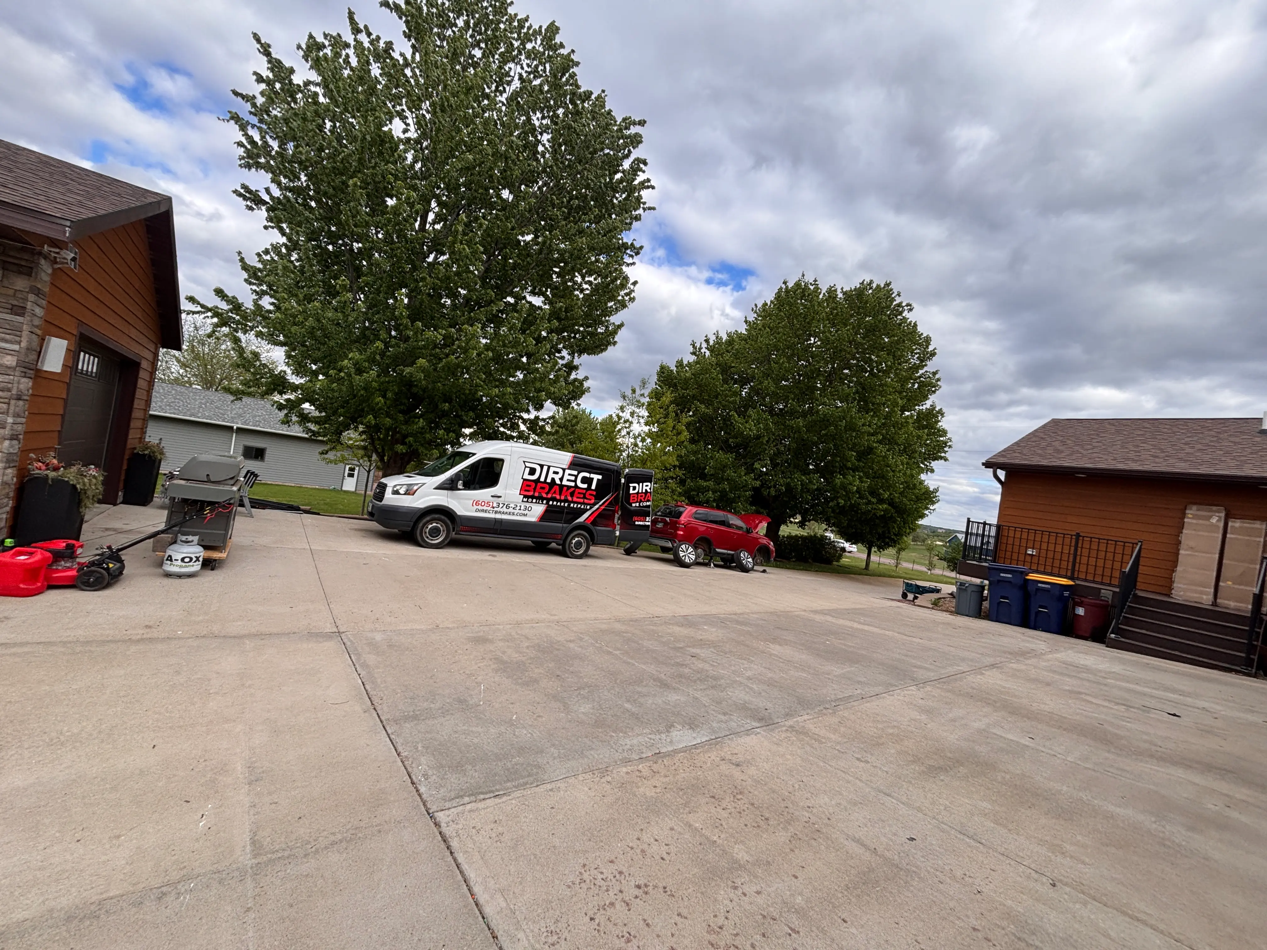 Direct Brakes technician performing mobile oil change in customer driveway